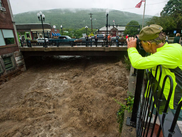 Mel Martin joins a crowd watching the raging Whetstone Brook surge over the falls in downtown Brattleboro, Vt. on  Aug. 28, 2011.  