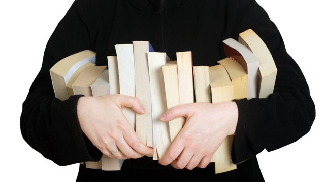 Model holding row of paperback books. 
