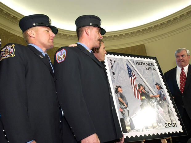 President George W. Bush unveils March 11, 2002, in the Oval Office of the White House in Washington the new postage stamp which uses the famous photo by Thomas E. Franklin of The Bergen (N.J.) Record of New York firefighters raising a flag at ground zero 