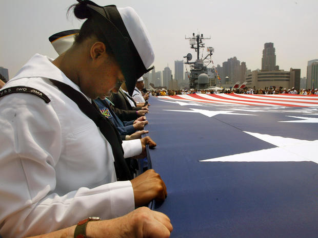 U.S. Navy Ensign Raquita Walker bows her head during the closing prayer of Memorial Day celebrations at the Intrepid Sea, Air and Space Museum during Fleet Week May 27, 2002, in New York City as she holds a giant American flag that flew over ground zero.  