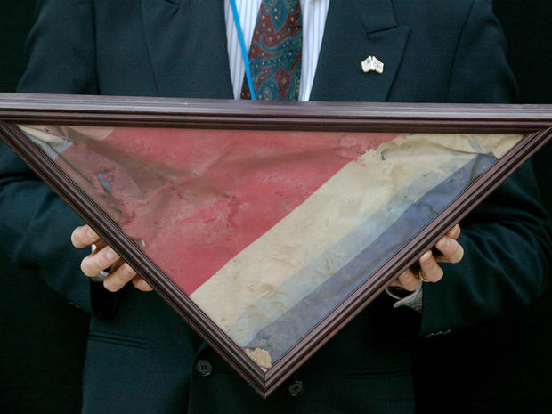 A U.S. Embassy official carries a British Union flag retrieved from the ruins at ground zero outside the U.S. Embassy Sept. 11, 2002, in London. The flag is presumed to have belonged to a British office worker who died at ground zero and was to be present 