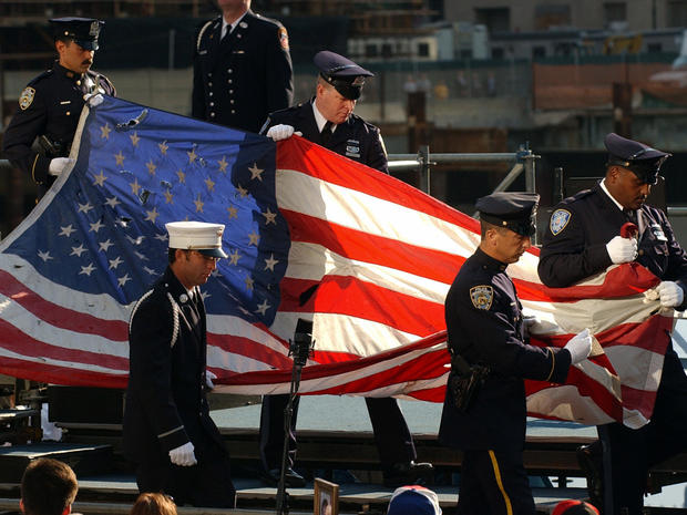 A U.S. flag that flew at the World Trade Center is carried off a stage by officers representing police and firefighters at ground zero during commemorations of the second anniversary of the terror attacks Sept. 11, 2003, in New York. The flag flew on boar 