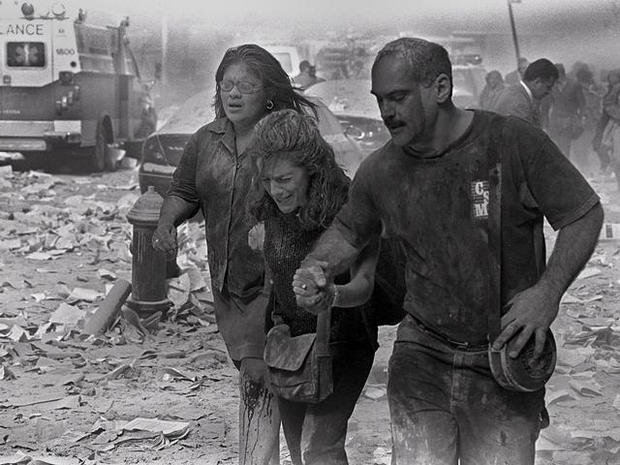 People walk through dust and debris from collapse of World Trade Center 