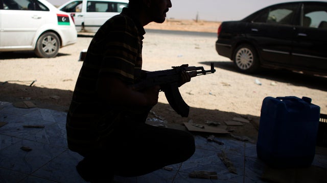 A rebel fighter takes cover against incoming fire from loyalists to Muammar Qaddafi in Bani Walid, Libya, Sept. 16, 2011. Libyan fighters are streaming into Bani Walid, one of Qaddafi's remaining bastions, in a new fierce push. 