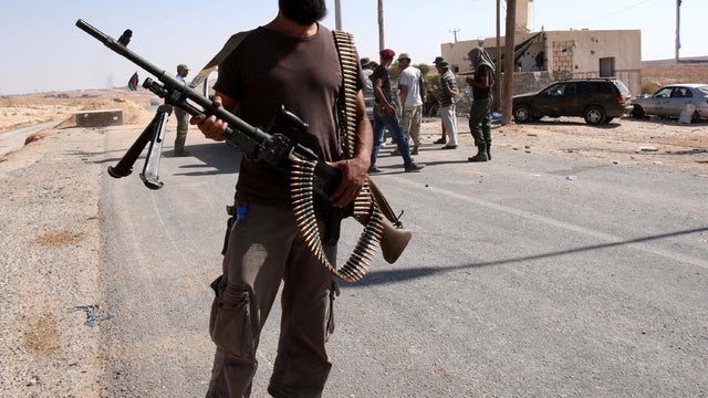 A Libyan Transitional National Council fighter stands with comrades on the road leading to the Bani Walid holdout southeast of the capital city of Tripoli Sept. 18, 2011, as progress in crushing the last pockets of resistance loyal to Libya's ousted leade 