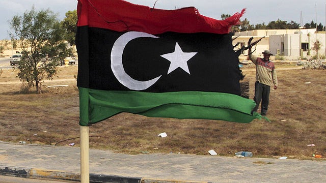 A revolutionary forces commander, Wajdi Badri, right, stands next to a pre-Gadhafi flag as he celebrates the new take over of the western main square in Sirte, Libya, Sept. 22, 2011.  