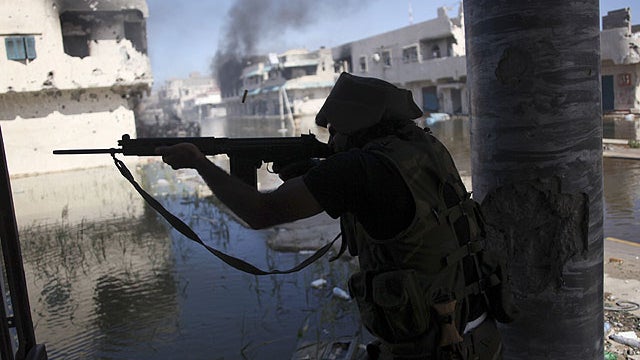 A Libyan revolutionary fighter fires with his machine gun while attacking pro-Gadhafi forces in downtown Sirte, Libya, Oct. 14, 2011. 