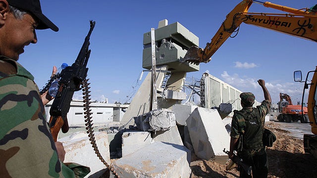 Revolutionary fighters use heavy machinery to tear down a guard tower at the Bab al-Aziziya compound in Tripoli, Libya, Oct. 16, 2011.  