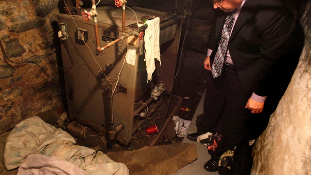 Philadelphia police Sgt. Joseph Green stands in the dank basement room in Philadelphia where four weak and malnourished mentally disabled adults, including one chained to the boiler, were found locked inside Oct. 17, 2011. Police arrested three adults sta 