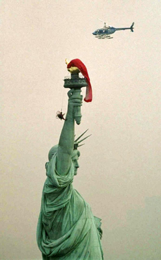 French adventurer Thierry Devaux hangs by the sail of his motorized parasail from the torch of the Statue of Liberty after an aborted attempt to land on the torch and bungee-jump toward New York Harbor Aug. 23, 2001, in New York. Police rescued Devaux and 