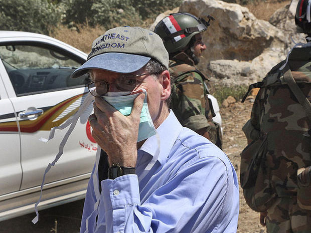 In this June 20, 2011 photo taken during a government-organized tour for foreign diplomats and the media, U.S. ambassador in Syria Robert Ford, covers his nose during his visit with other foreign diplomats to a mass grave, in Jisr el-Shughour, north of Syria. 