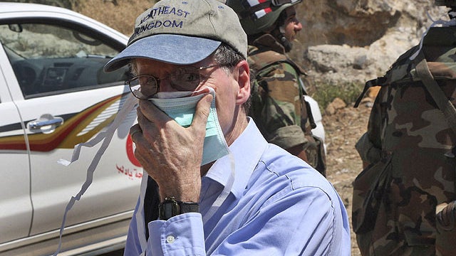In this June 20, 2011 photo taken during a government-organized tour for foreign diplomats and the media, U.S. ambassador in Syria Robert Ford, covers his nose during his visit with other foreign diplomats to a mass grave, in Jisr el-Shughour, north of Sy 