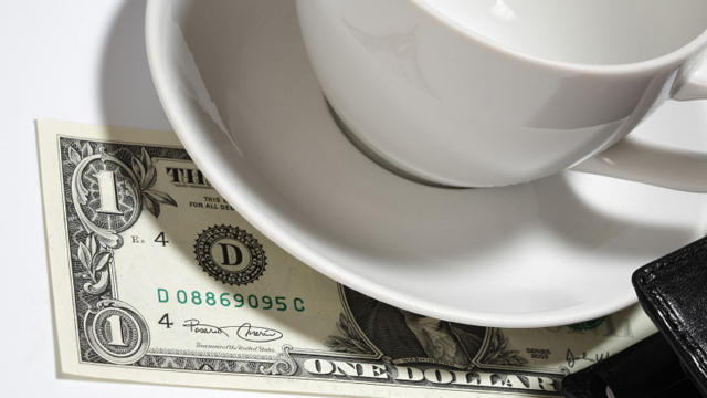 Closeup of one dollar, tea cup, saucer and wallet 