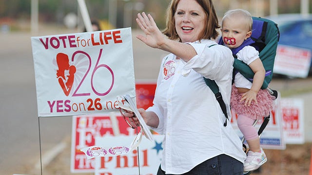 Amendment 26 supporter Joyce Haskins, with her grandchild Landry Bruce, waves to passersby outside the voting booths at the Oxford Conference Center in Oxford, Miss. on Nov. 8, 2011.  