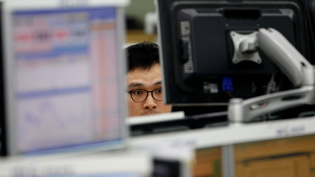 Currency trader looks at monitors of foreign exchanges  
