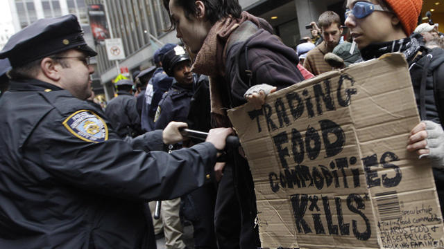 A police officer shoves demonstrators affiliated with the Occupy Wall Street movement as they block an entrance to the New York Stock Exchange Nov. 17, 2011, in New York. 