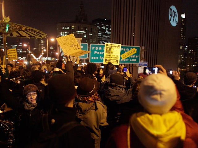 Protesters affiliated with the Occupy Wall Street movement watch a projection on the side of the Verizon tower as they march across the Brooklyn Bridge in New York City Nov. 17, 2011. 