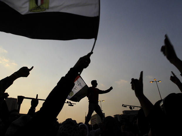 Egyptian protesters wave their national flags as they chant slogans  
