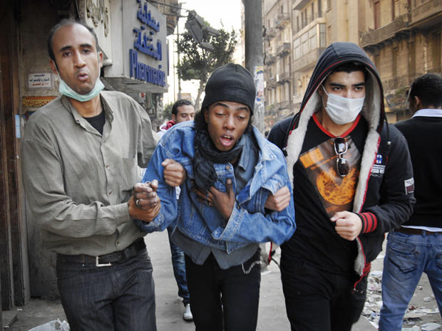 protesters accompany a man overcome with tear gas inhalation 