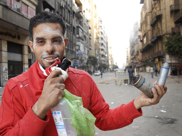 An Egyptian protester holds canisters 