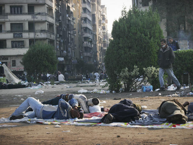Egyptian Protester walks past men who spent the night in Tahrir square 