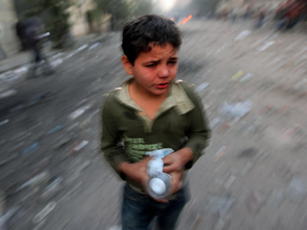 Egyptian boy holds a mask and bottle of water as he runs for cover  