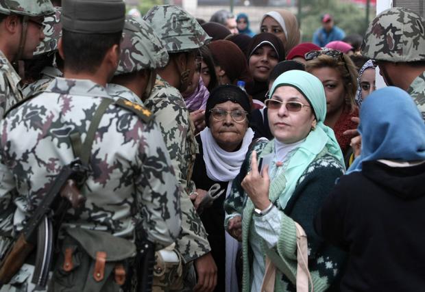 Egyptian women walk past soldiers as they arrive to vote 