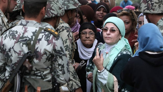 Egyptian women walk past soldiers as they arrive to vote 
