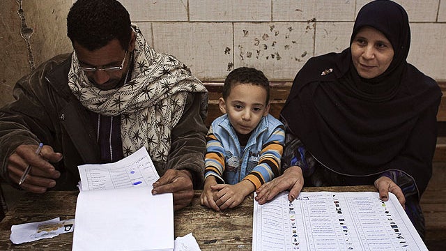 An election official sits with her son at a polling station near the town of Ibshawai, near Fayoum, 62 miles southwest of Cairo, Egypt, Nov. 29, 2011.  