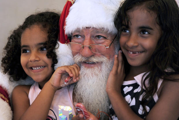 A Santa Claus poses with two children in 