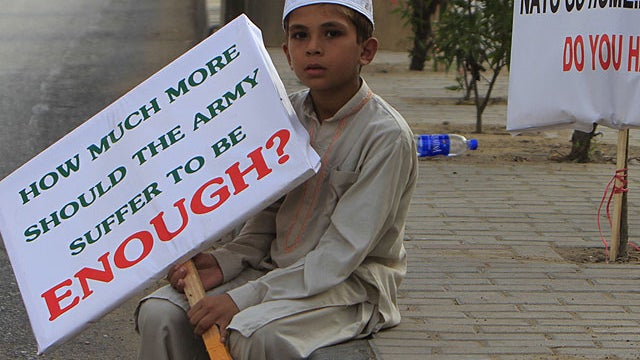 A Pakistani religious student sits at a roadside as others rally to condemn killings of Pakistani troops in a NATO airstrikes, in Karachi, Pakistan on Dec 1, 2011. 