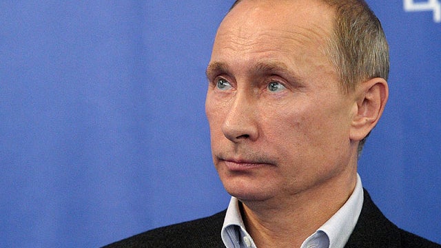 Prime Minister Vladimir Putin, with the emblem of the United Russia party in the background, visits the United Russia party headquarters in Moscow, Dec. 4, 2011.  