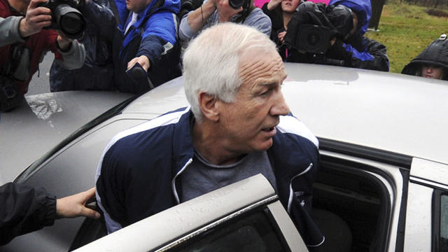 Jerry Sandusky is escorted to a police car 