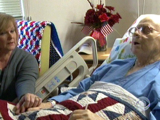 Barbara Stadler, a Veterans Affair employee who volunteers at the hospital's end-of-life program, holds the hand of Korean war vet Richard Murley. 