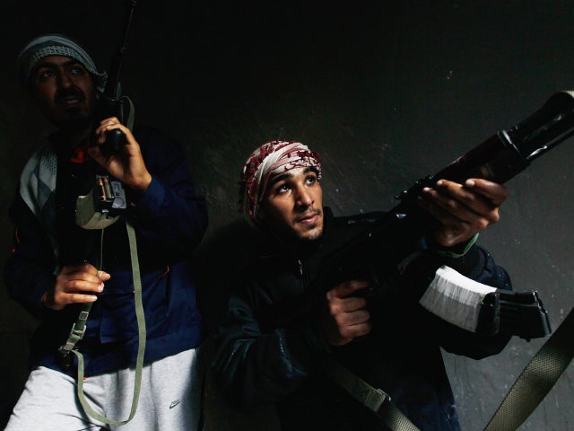 Rebel fighters carefully move into a building  