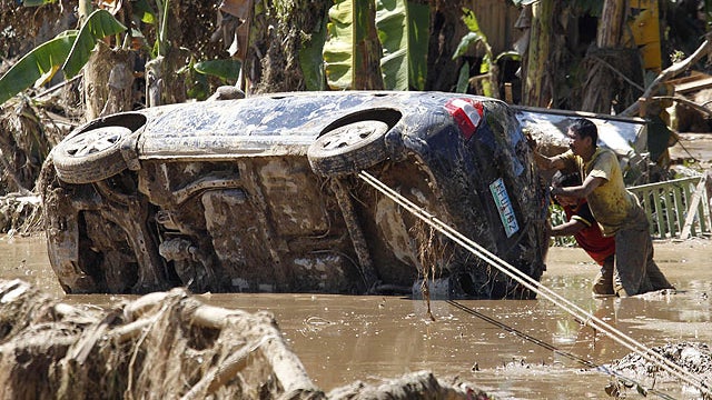 Residents retrieve a car which was washed away in Friday's flash flooding in Iligan city in southern Philippines, Dec. 19, 2011.  