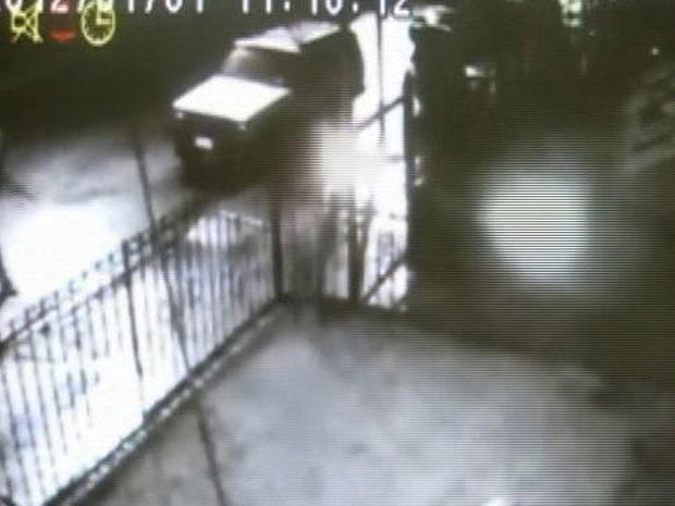 In this frame grab taken from surveillance video released by the NYPD, a suspect, left, throws a lit object at a home in the Queens borough of New York on Sunday night, Jan. 1, 2012. 