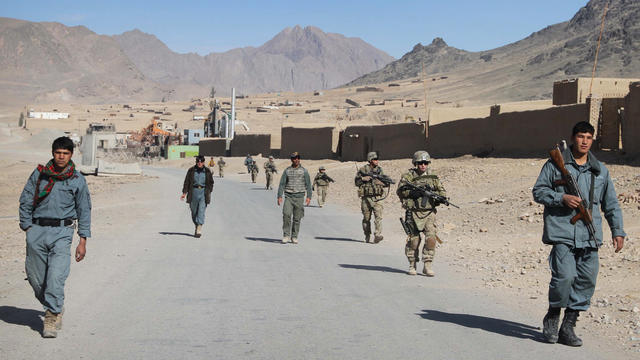 Afghan policemen walk ahead of U.S. soldiers during a foot patrol in Kandahar 