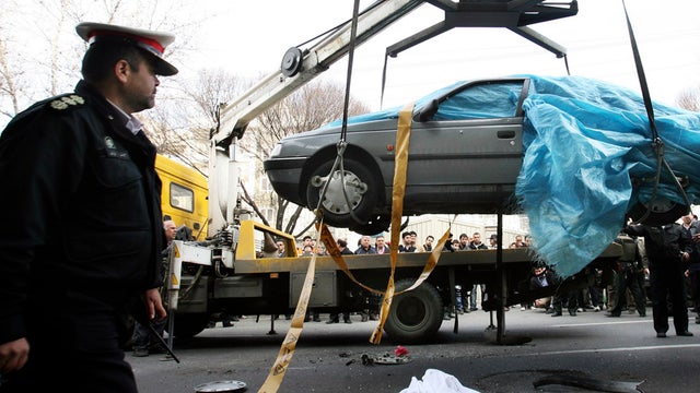 People gather around a car as it is removed by a mobile crane in Tehran, Iran, Jan. 11, 2012, in this photo provided by the semi-official Fars News Agency. Two assailants on a motorcycle attached magnetic bombs to the car of an Iranian university professo 