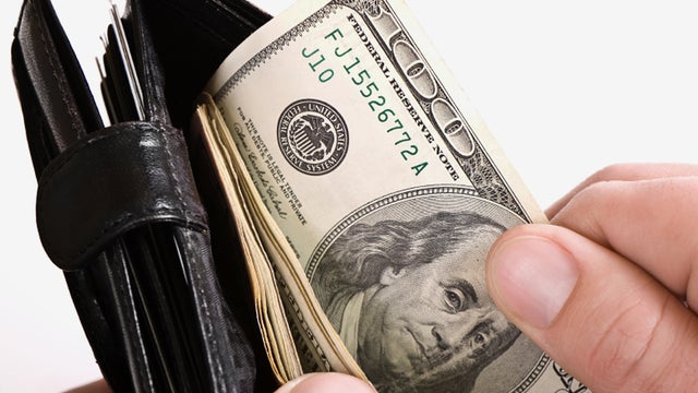 Man holding a wallet with cash in it. 