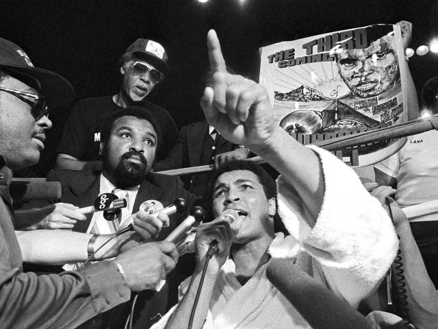 Muhammad Ali shouts while someone holds a poster 