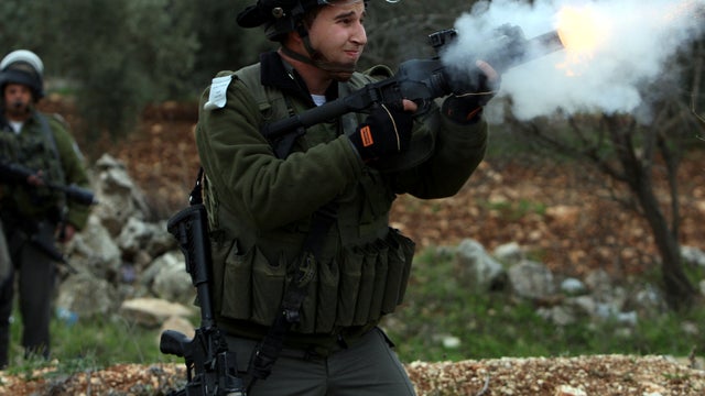 An Israeli soldier fires his weapon at Palestinian youths during clashes following a protest against Israel's controversial separation barrier in Qalandia near the West Bank city of Ramallah Dec. 30, 2011. 