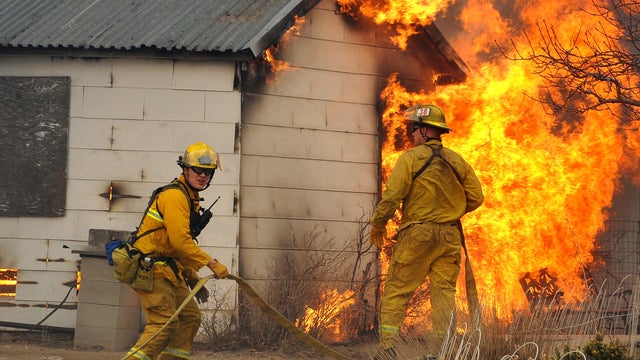 Firefighters wait for water before attacking an outbuilding adjacent to a home 