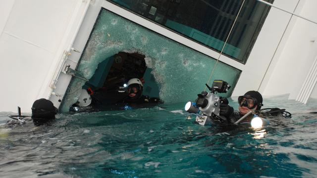 Italian scuba divers swim around the wreck of the Costa Concordia 