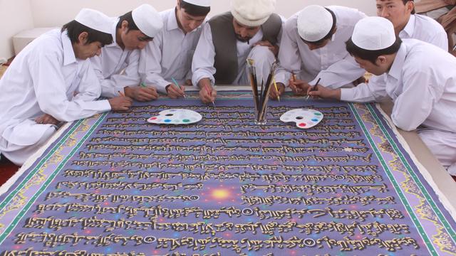 Afghan calligrapher Mohammed Sabeer Hussani, center, and nine student apprentices work on a page for the world's largest Quran 