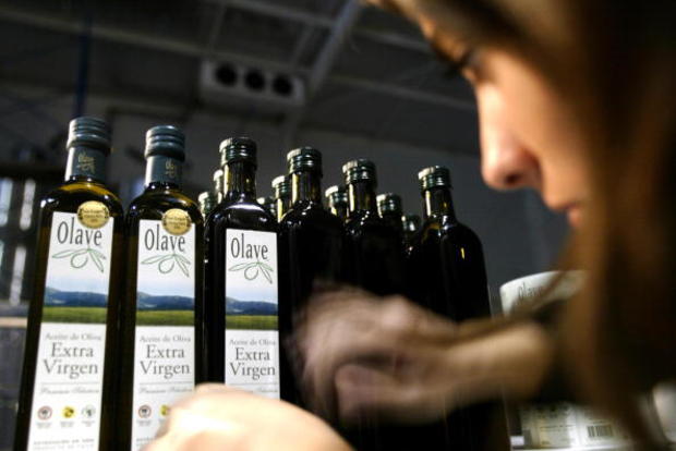A woman glues labels on olive oil bottle 