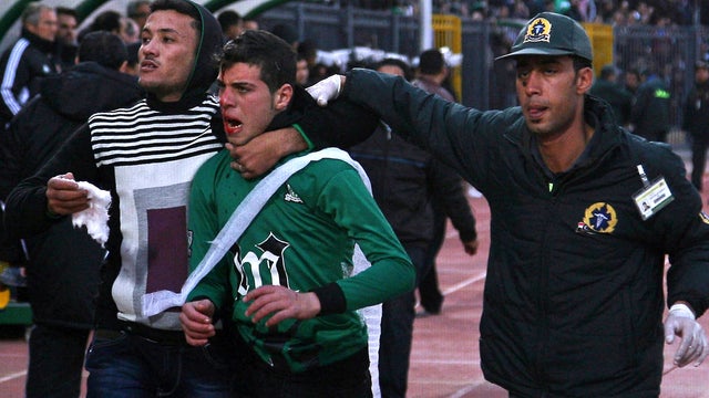A wounded Al-Masry fan is escorted by a medic and a friend 