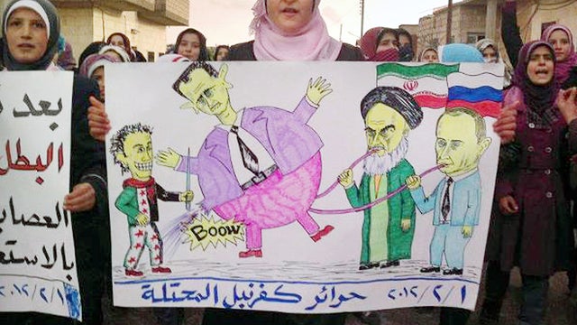 An anti-Syrian-regime protester holds a poster with a caricature depicting the Russian Prime Minister Vladimir Putin, right, and Iranian supreme leader Ayatollah Ali Khamenei, second right, pumping up their ally Syrian President Bashar Assad, center, as t 