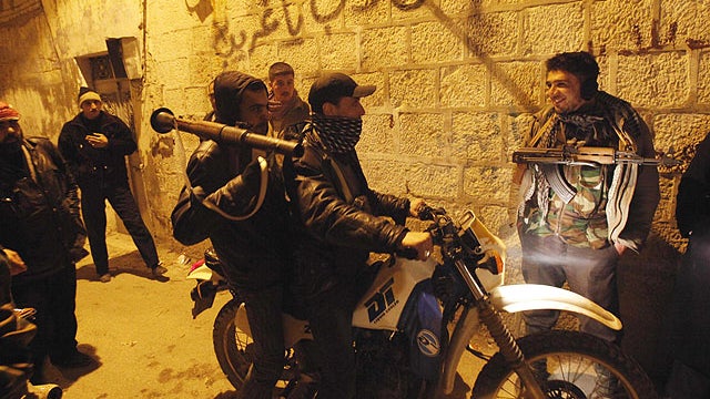 In this Feb. 5, 2012 photo, Syrian rebels gather in an alley as they secure a demonstration in Idlib, Syria.  