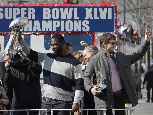Justin Tuck holds the Vince Lombardi Trophy, and Eli Manning, holding the Halas Trophy 